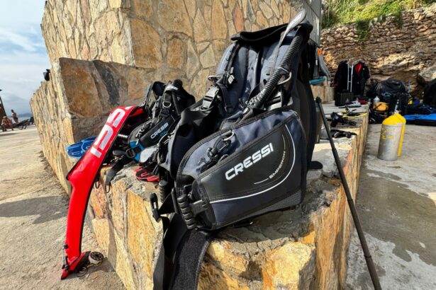 Cressi Emperor BCD propped against a stone wall at a shore dive site with gear staged around it