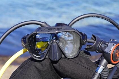 Cressi Z2 mask resting on a BCD with regulator hoses looped around it and the sea behind