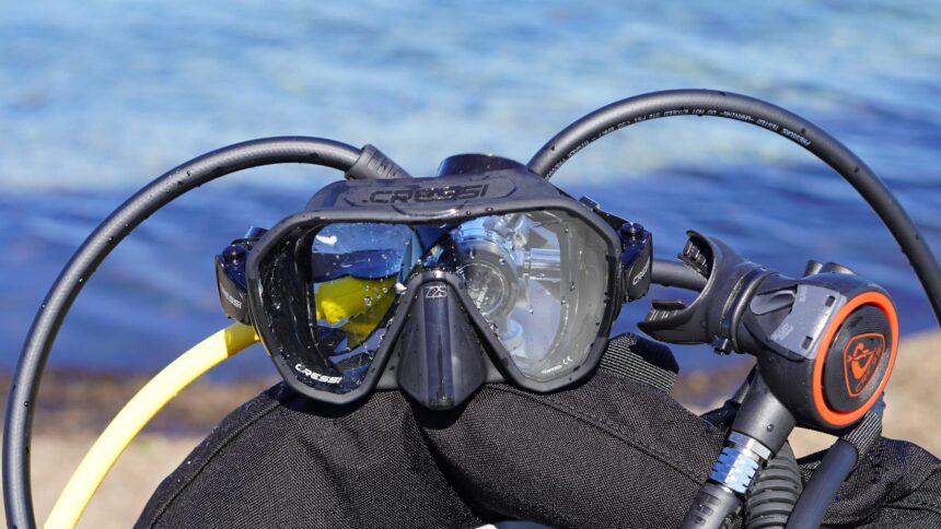 Cressi Z2 mask resting on a BCD with regulator hoses looped around it and the sea behind
