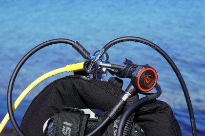 Cressi AC5 first stage and Zen second stage mounted on a black BCD beside blue water
