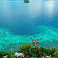 Aerial view of Fatboys Resort's overwater bungalow and turquoise reef lagoon in the Solomon Islands