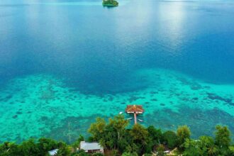 Aerial view of Fatboys Resort's overwater bungalow and turquoise reef lagoon in the Solomon Islands