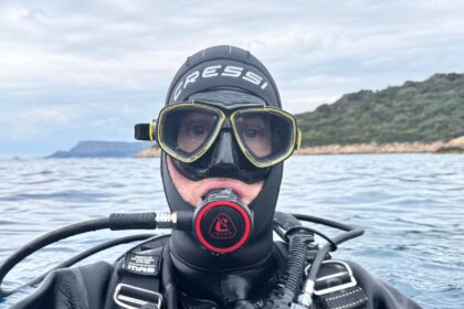 DIVEIN tester floating at the surface in a Cressi hood and mask with the regulator in his mouth