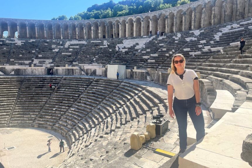 Visitor standing on the stone terraces of the ancient Aspendos theater in Turkey
