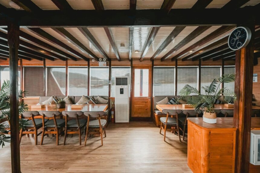 wood-beamed dining and lounge area aboard the Indo Master liveaboard with tables set for guests