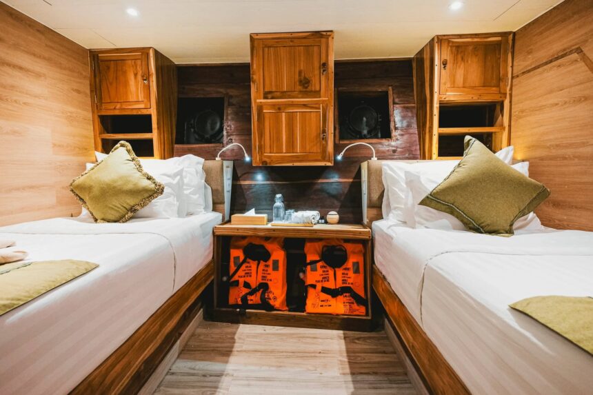twin bunks with life jackets stored beneath a shared nightstand on the Indo Master