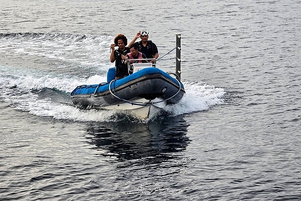 dive tender speeding across the water with divers aboard near the Indo Master