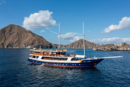 The Indo Master liveaboard anchored near a mountainous, forested coastline
