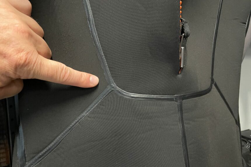 Our reviewer pointing at the taped seams on the black Apeks ThermiQ 5 mm wetsuit