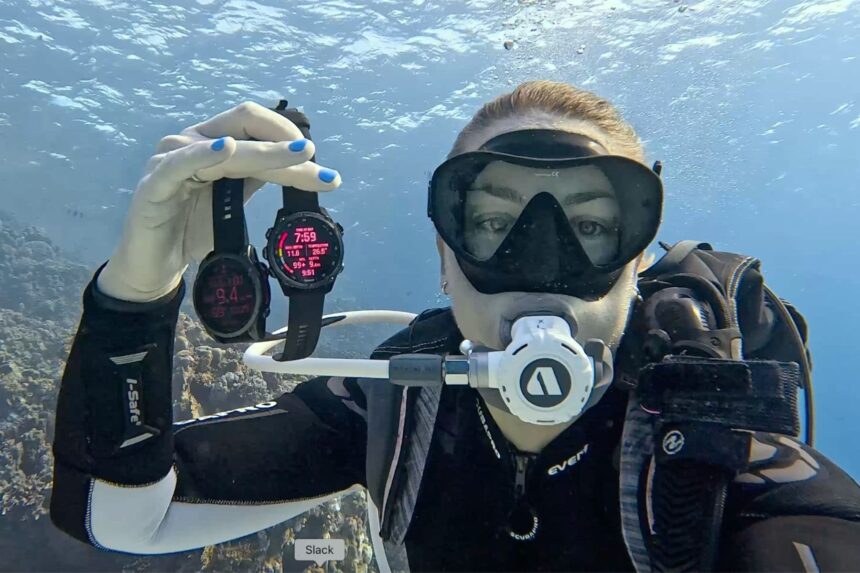 Scuba tester Sylvia holding up two dive computers for the camera during a reef dive