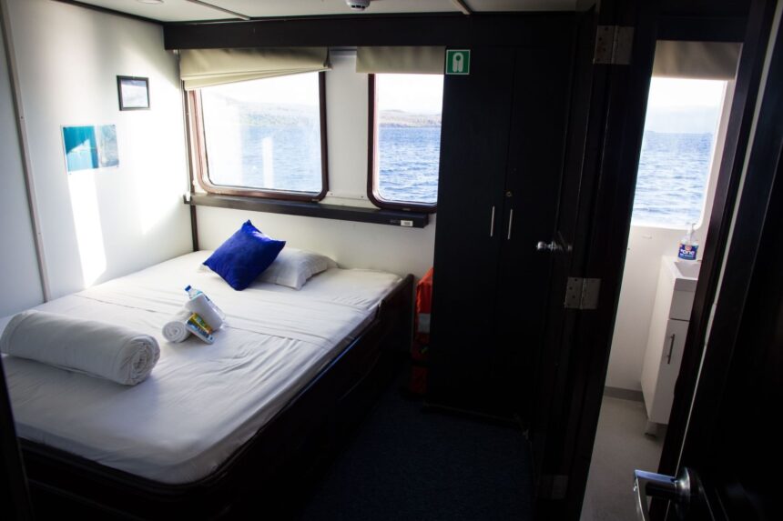 Ensuite cabin aboard the Galapagos Master with a made-up bed and ocean-view windows