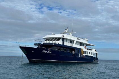 The Galapagos Master liveaboard yacht Deep Blue anchored under a cloudy sky