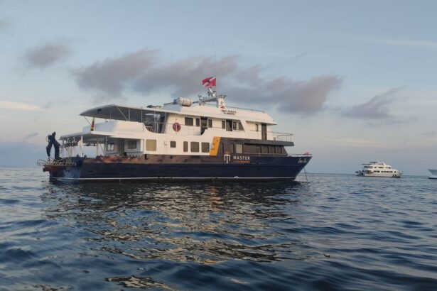 The Galapagos Master liveaboard anchored at sea at dusk with another yacht nearby