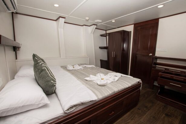 Wood-paneled cabin with a made-up double bed, wardrobe and folded towels