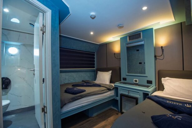 Blue-toned cabin with twin beds and an open door leading to the ensuite bathroom