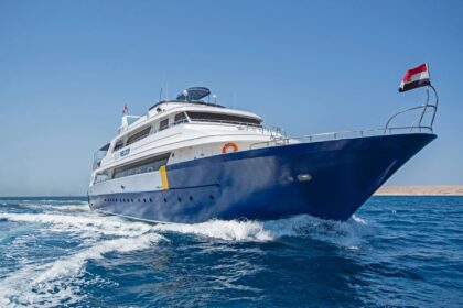 The Blue Melody liveaboard cruising with its bow wake and an Egyptian flag astern