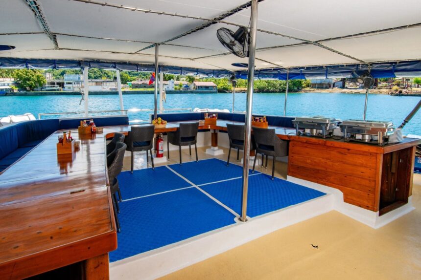 Outdoor buffet dining setup on deck with chafing dishes and woven seating