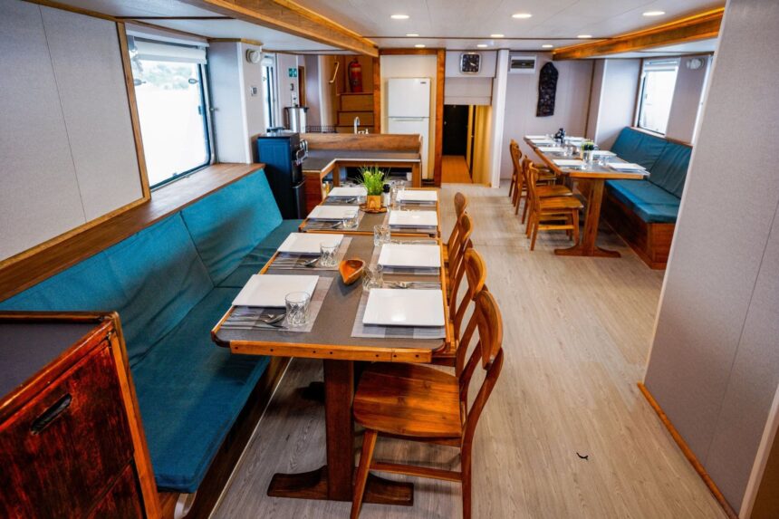 Dining tables and blue booth seating in the Solomons Master's saloon