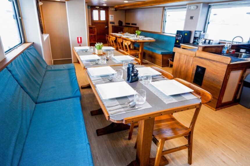 Dining area aboard the Solomons Master with tables set for a meal and an open galley