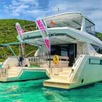 Catamaran with BVI Wreck Week banner flags moored in turquoise water off Cane Garden Bay