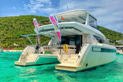 Catamaran with BVI Wreck Week banner flags moored in turquoise water off Cane Garden Bay