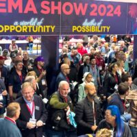 Crowd of attendees gathered under the DEMA Show entrance signage