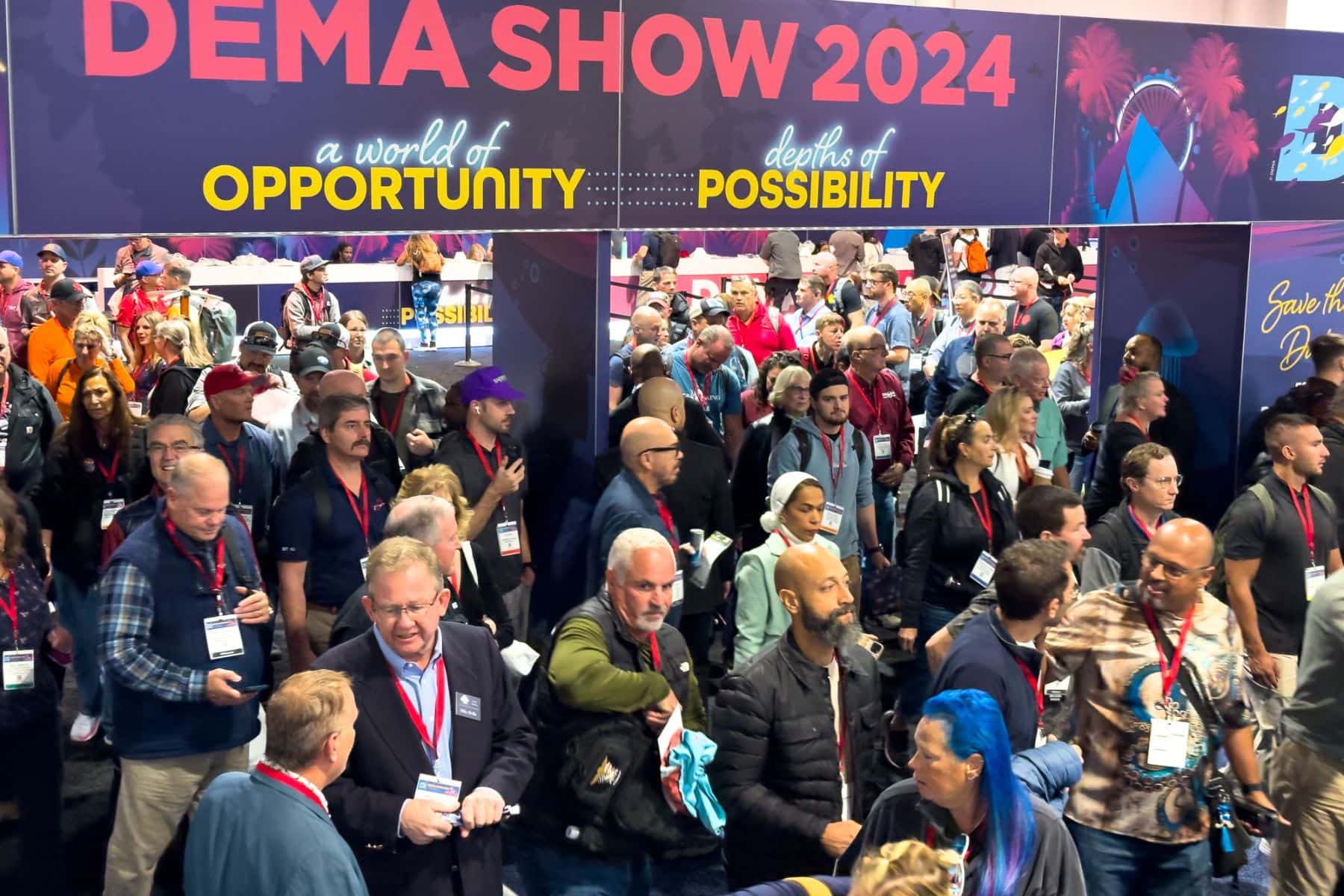 Crowd of attendees gathered under the DEMA Show entrance signage