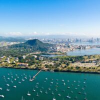 Aerial view of Panama City with sailboats moored along the green coastline and the skyline behind