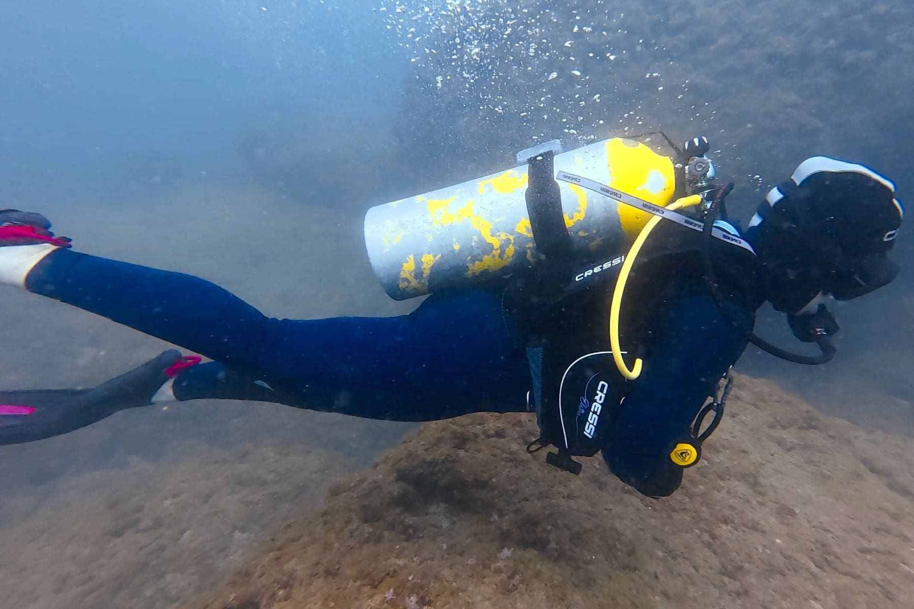 DIVEIN tester finning in the Cressi Comfort 5 mm wetsuit over a rocky bottom