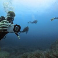 DIVEIN tester holding the white Oceanic+ housing up to frame a photo during a test dive