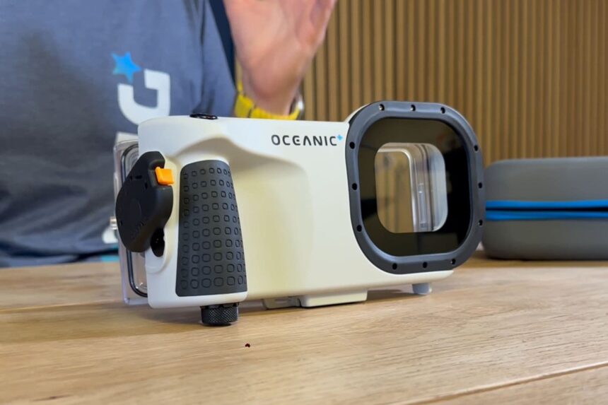 Oceanic+ underwater iPhone housing standing on a wooden table, showing the grip and port
