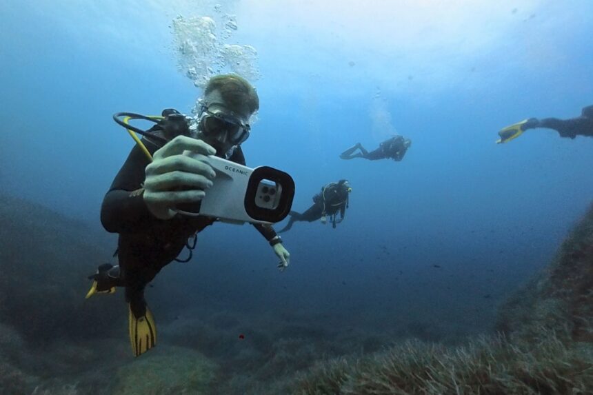 Diver Using An Oceanic Phone Housing Diver holding an Oceanic phone housing to photograph other divers underwater
