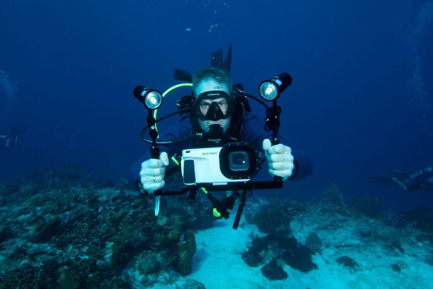 Diver Shooting With Housing And Lights Diver on a reef aiming the Oceanic+ iPhone housing on a tray with twin video lights