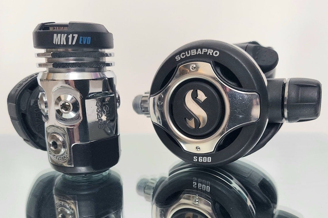 ScubaPro MK17 EVO first stage next to the S600 second stage on a reflective black surface