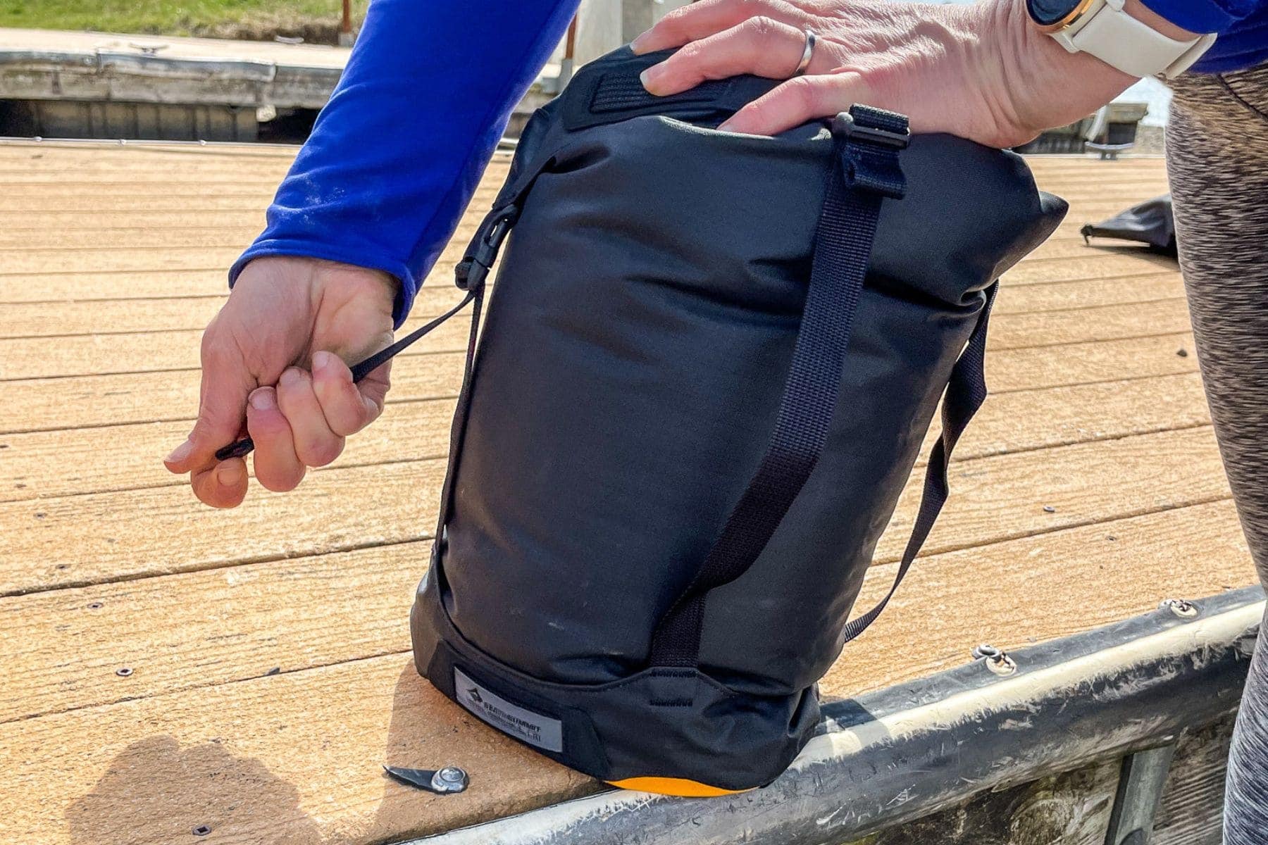 Our tester steadying the Sea to Summit EVAC Compression HD dry bag upright on a wooden dock
