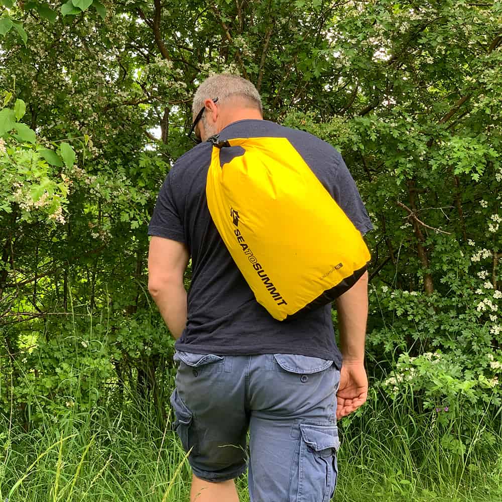 Our tester walking a green trail with the yellow Sea to Summit Sling Lightweight worn across his back