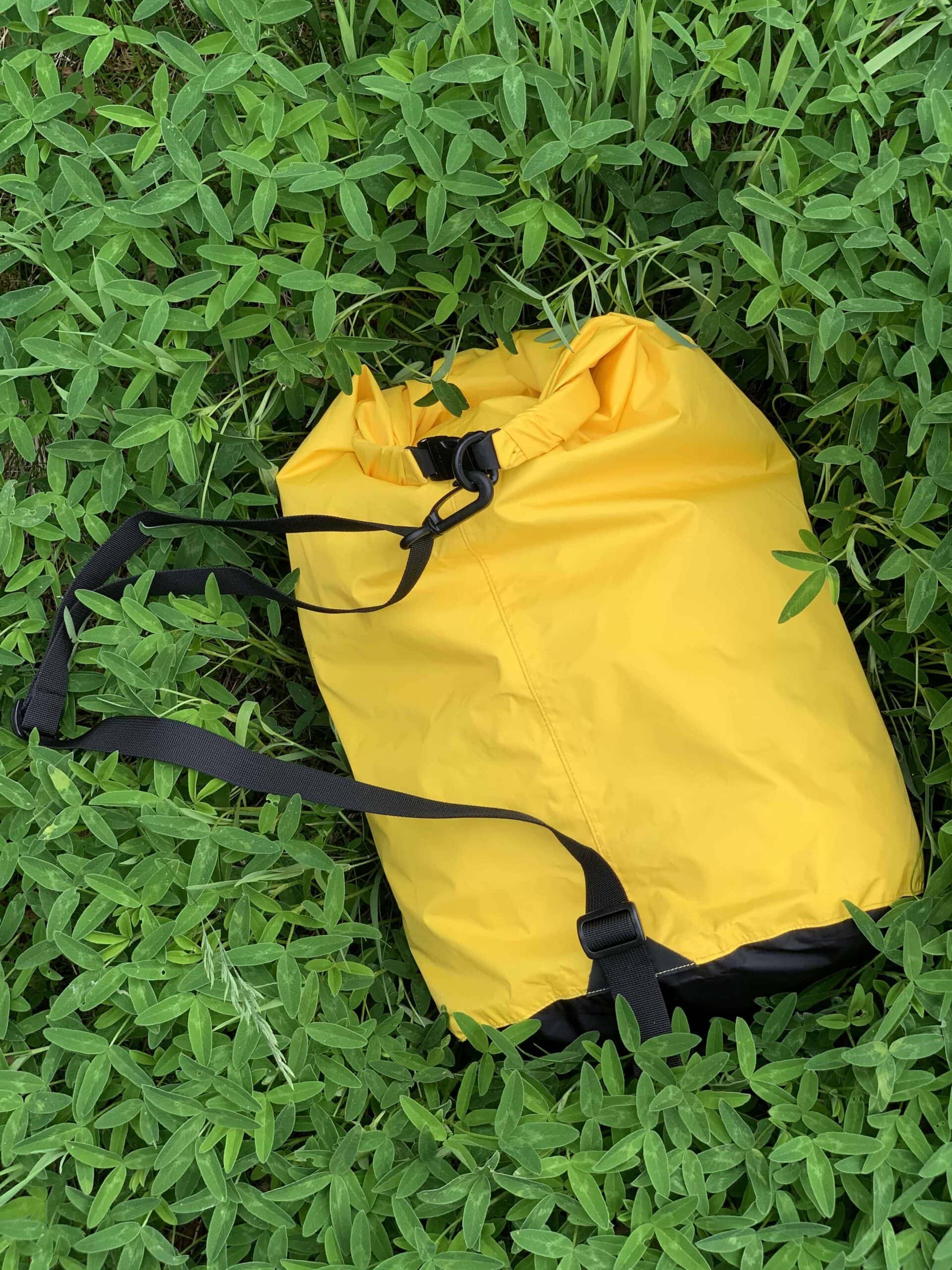 Sea to Summit Sling Lightweight rolled shut on grass with its black sling strap stretched out