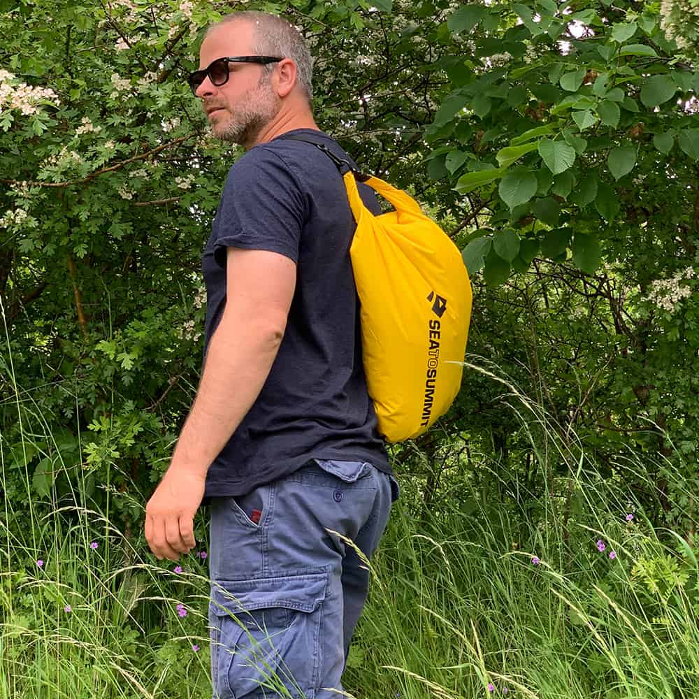 DIVEIN tester carrying the Sea to Summit Sling Lightweight on one shoulder beside a hedgerow