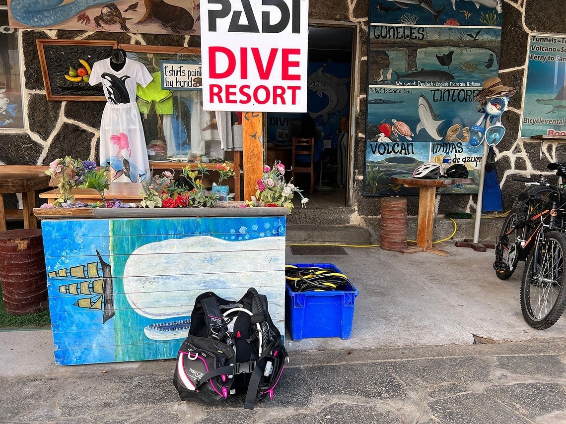 TUSA Tina BCD on the ground outside a PADI dive resort shop front with painted signs