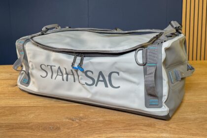Stahlsac Abyss duffel bag on a wooden table showing its lid zip, haul handles and side straps