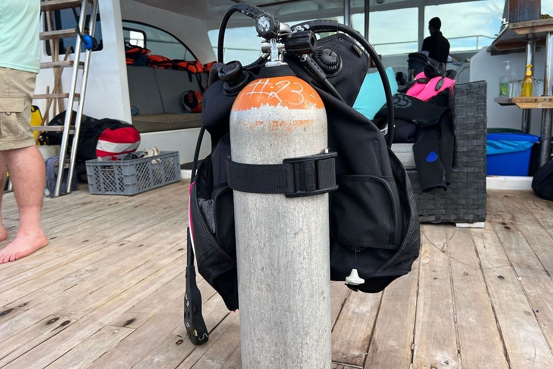 TUSA Tina BCD standing on a boat deck with a numbered dive tank held by the RiteTite buckle