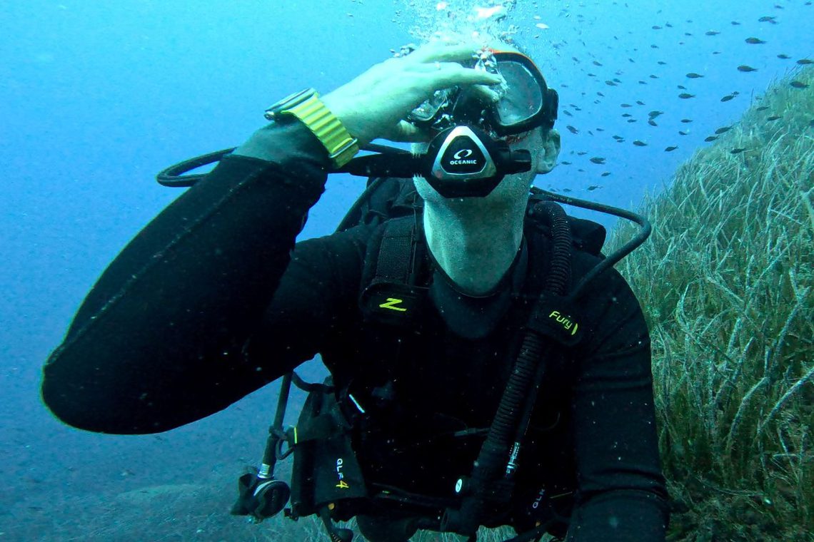 DIVEIN tester adjusting his mask underwater while wearing the Zeagle Fury BCD above a seagrass bed