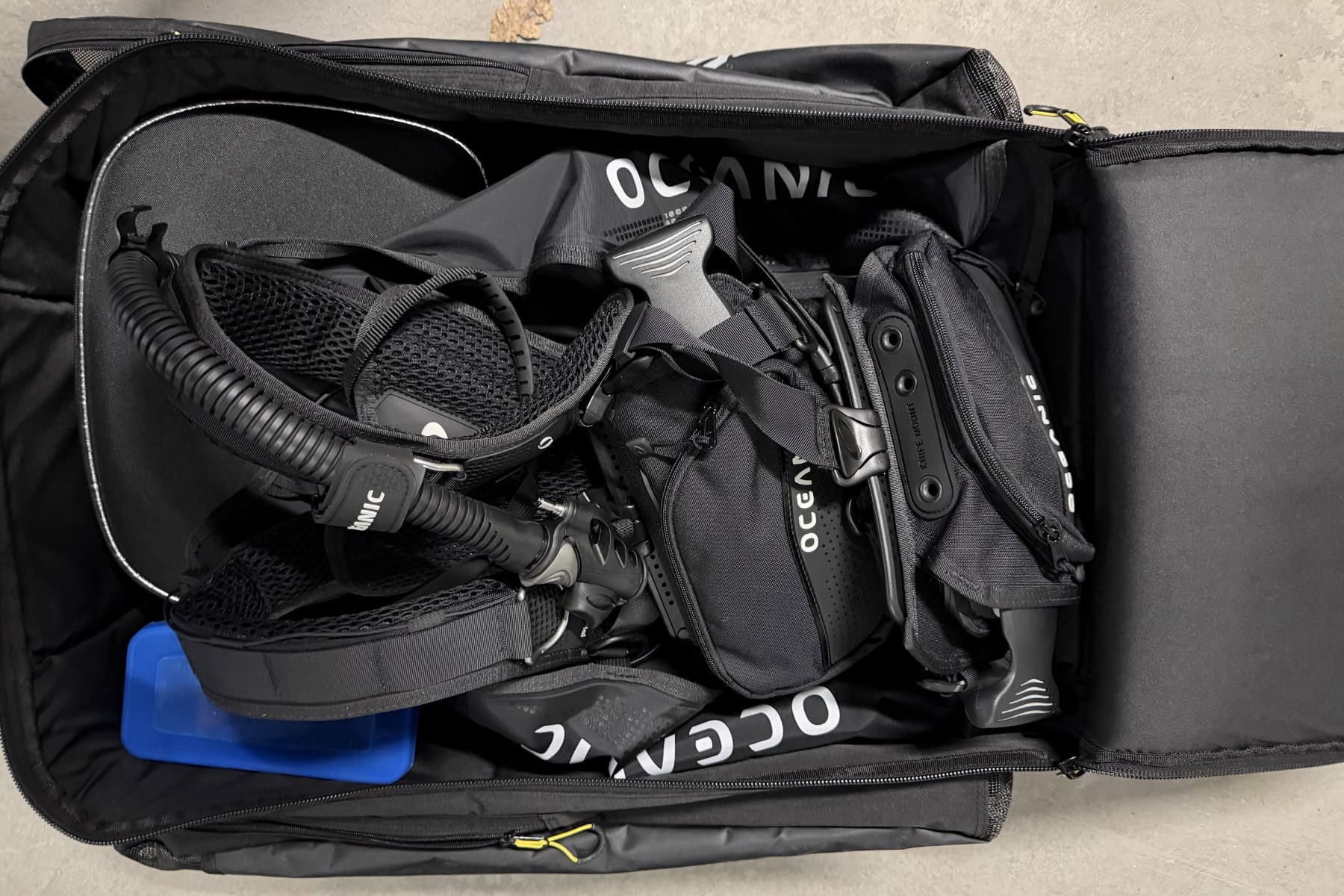 Oceanic Photon Pro packed into a dive bag with a regulator, hose and a blue weight block