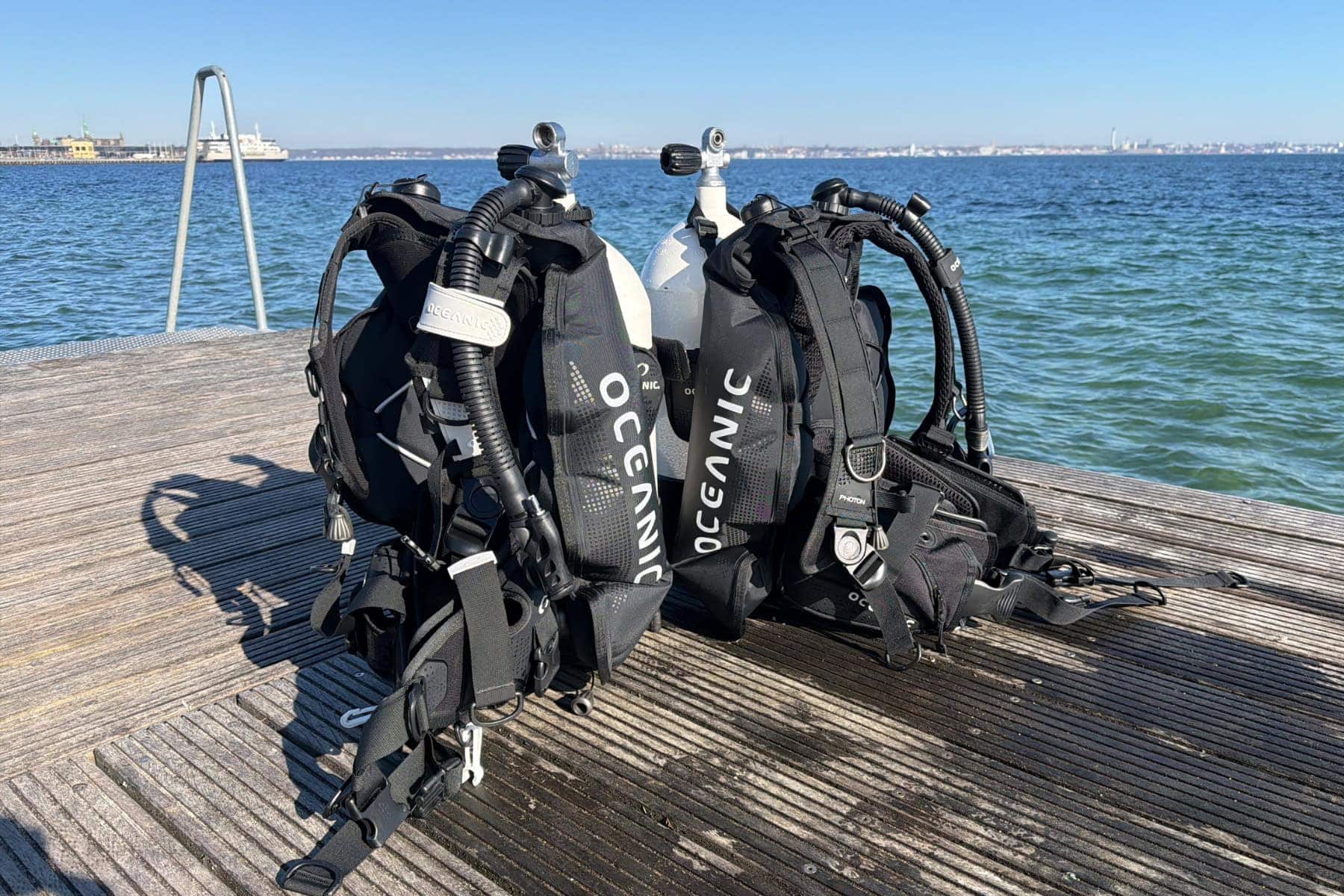 Oceanic Photon Pro and Photon Air BCDs standing side by side on a dock beside the sea