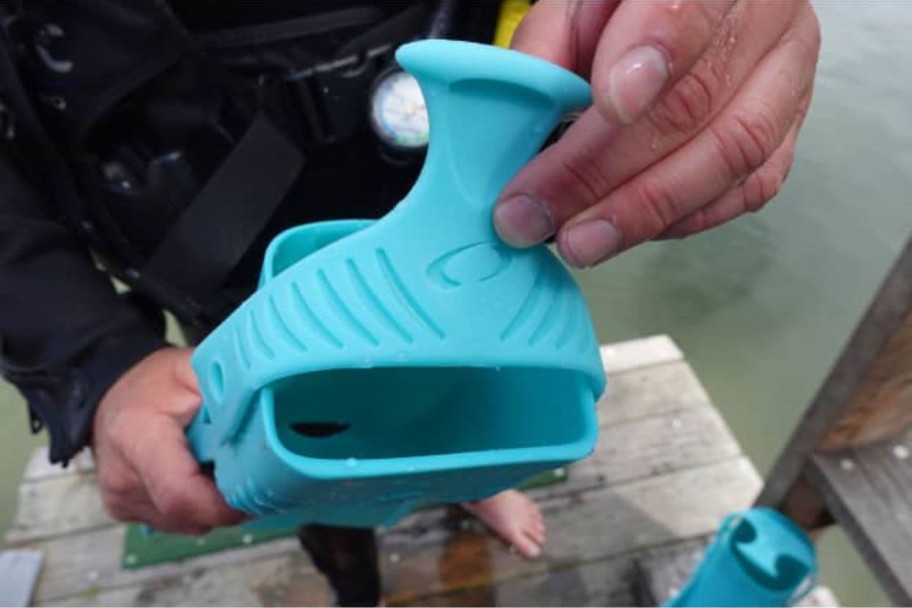 Our tester holding up the turquoise Oceanic Accel open-heel fin to show the foot pocket and strap
