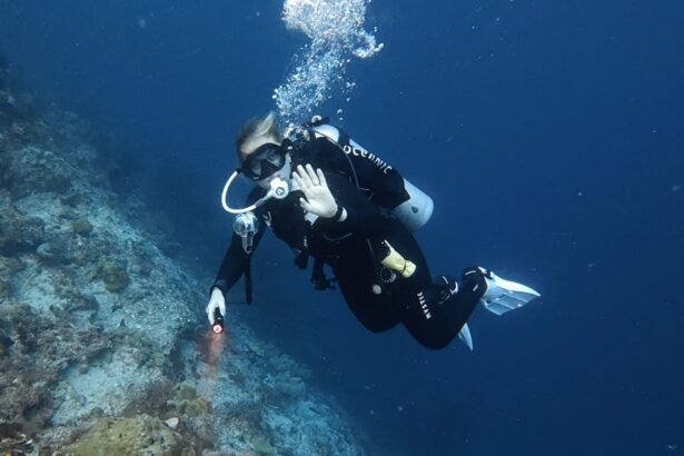 Tester waving with a dive light while wearing the Oceanic Photon Air on a wall dive