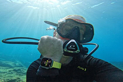 DIVEIN tester underwater checking the Apple Watch Ultra running Oceanic+ on his wrist mid dive