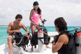 Divers and a boat crew gearing up scuba tanks on a sunny dive boat
