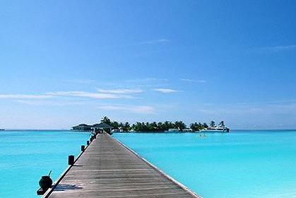 Wooden jetty stretching toward a tropical island across turquoise water