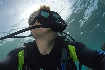 Scuba diver looking up toward sunlight filtering through the water surface